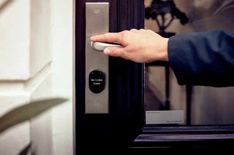 Main ouvrant une porte équipée d'une serrure connectée
