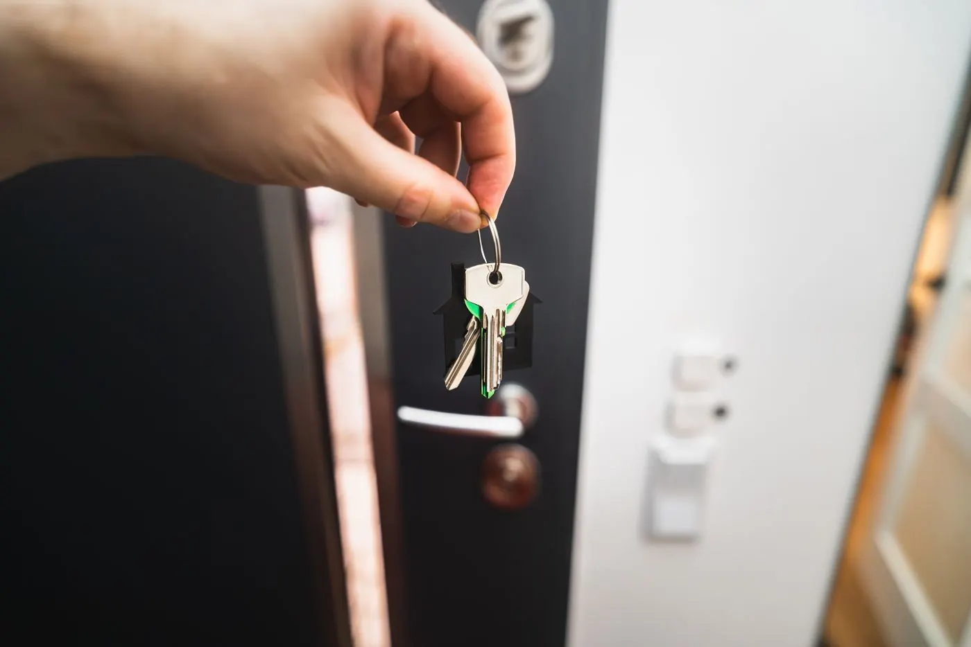 Main tenant des clés devant une porte d'entrée