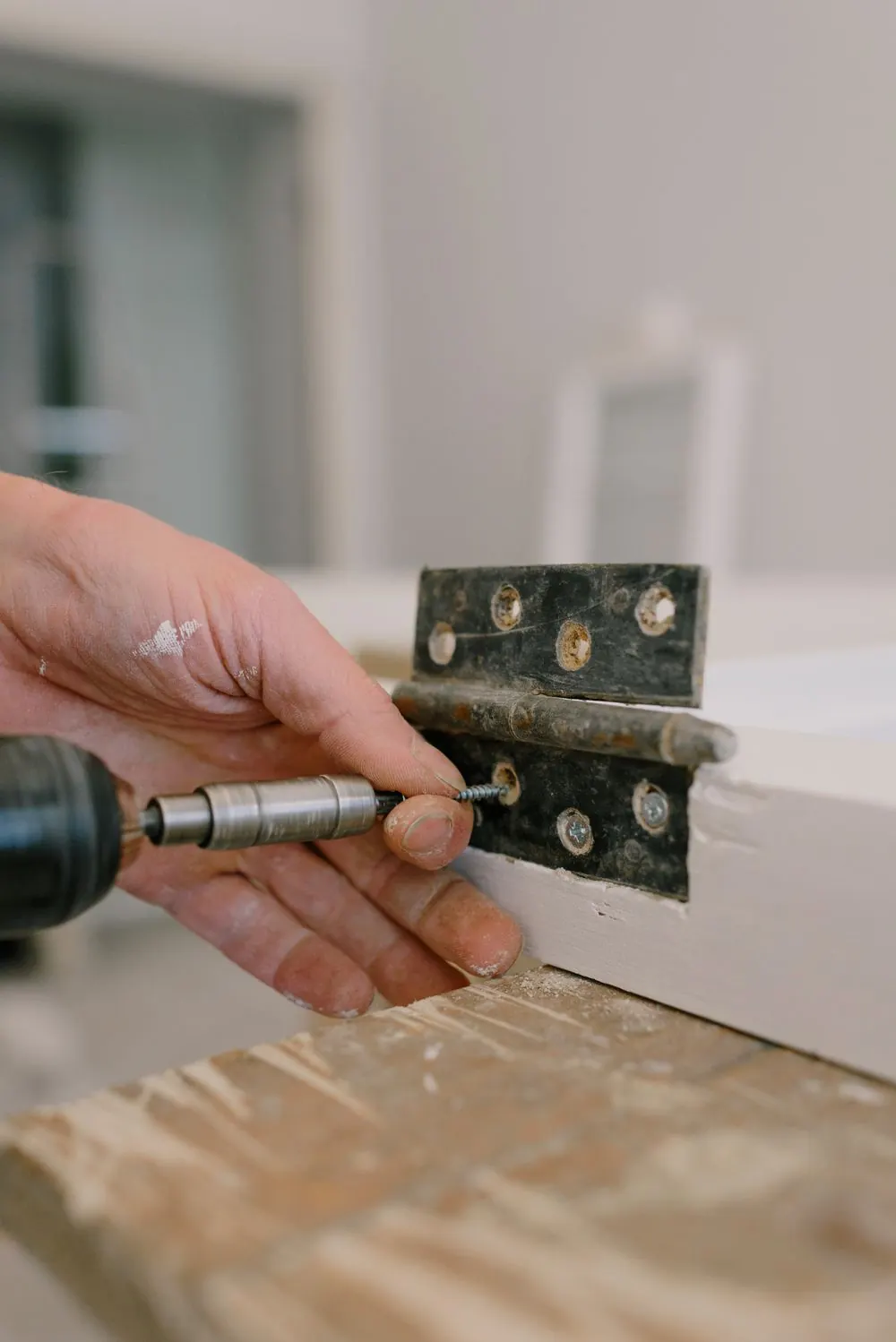 Artisan fixant une ferrure de porte à la visseuse